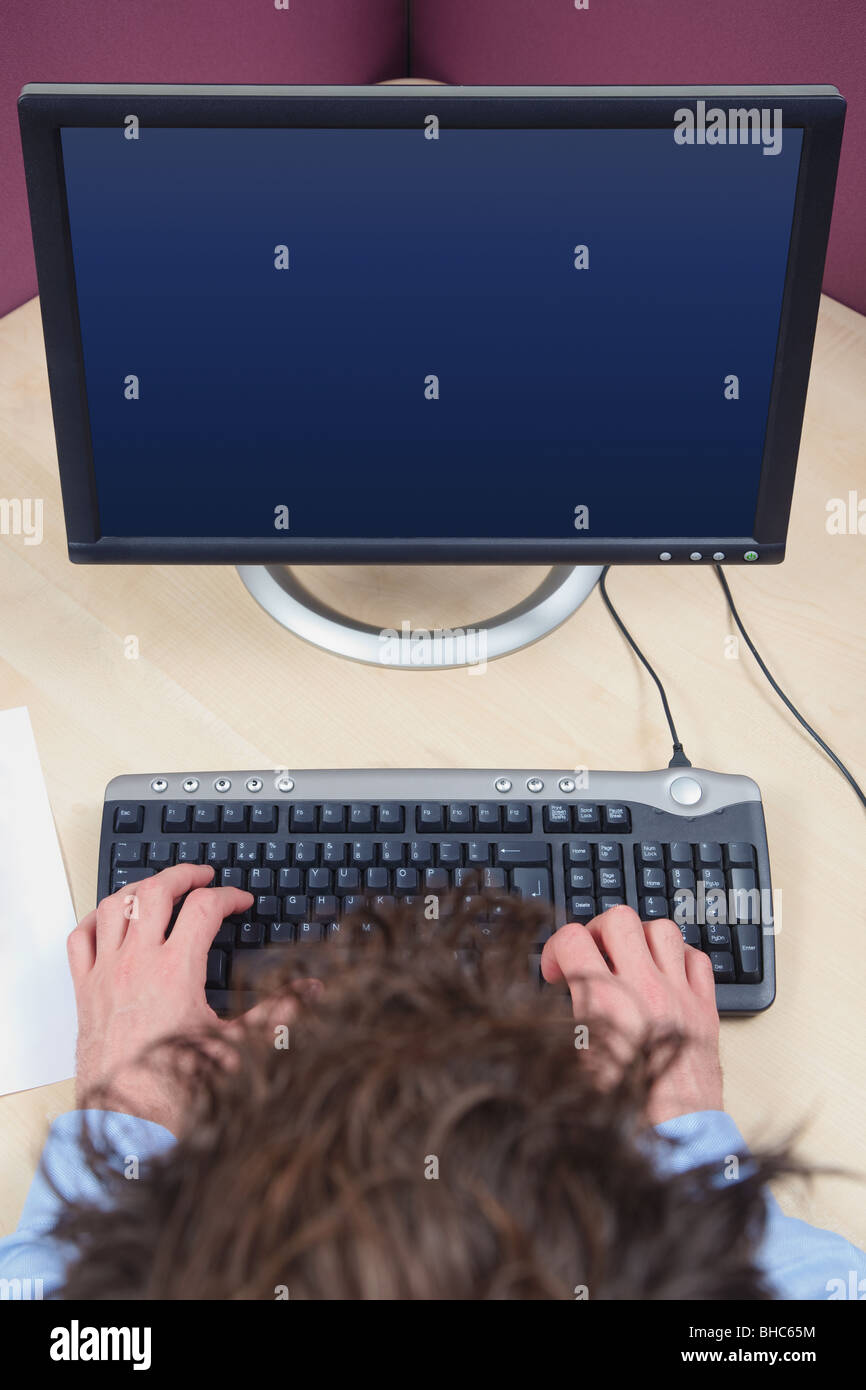A man working on a computer, overhead shot, blank screen with clipping path to add your own image. Stock Photo