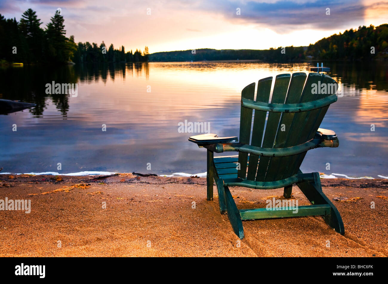 Wooden chair on beach of relaxing lake at sunset Stock Photo - Alamy