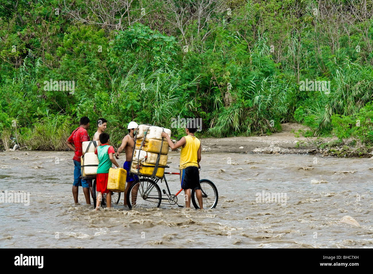 Colombian smugglers searching for the best way to cross the river Táchira with bicycles loaded with the Venezuelan gasoline. Stock Photo