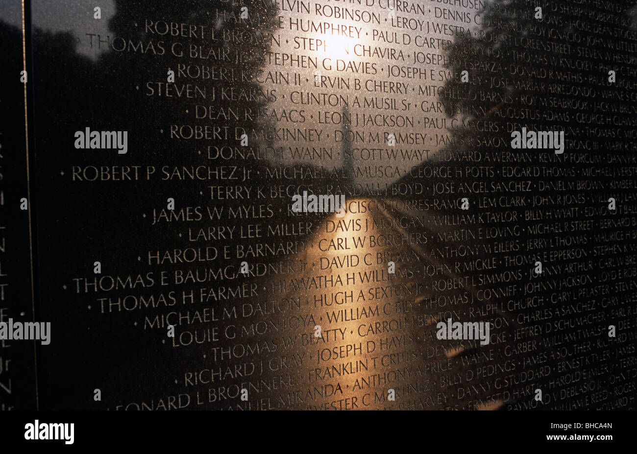 The names of those killed at the Washington DC Vietnam Memorial are picked out against a rising above the Washington Memorial Stock Photo