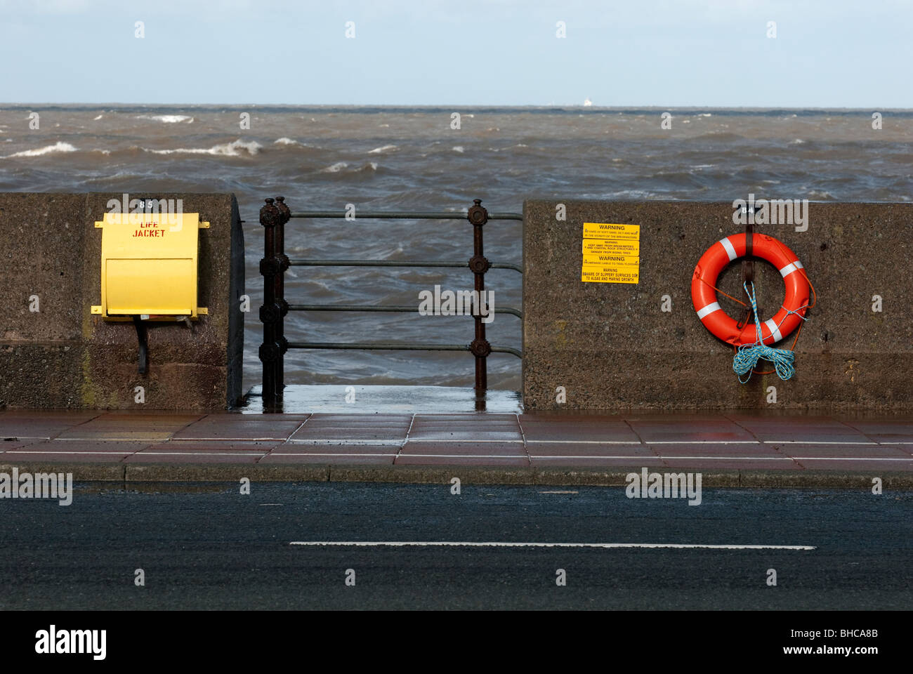 Life ring and lifejacket on sea wall near steps Stock Photo