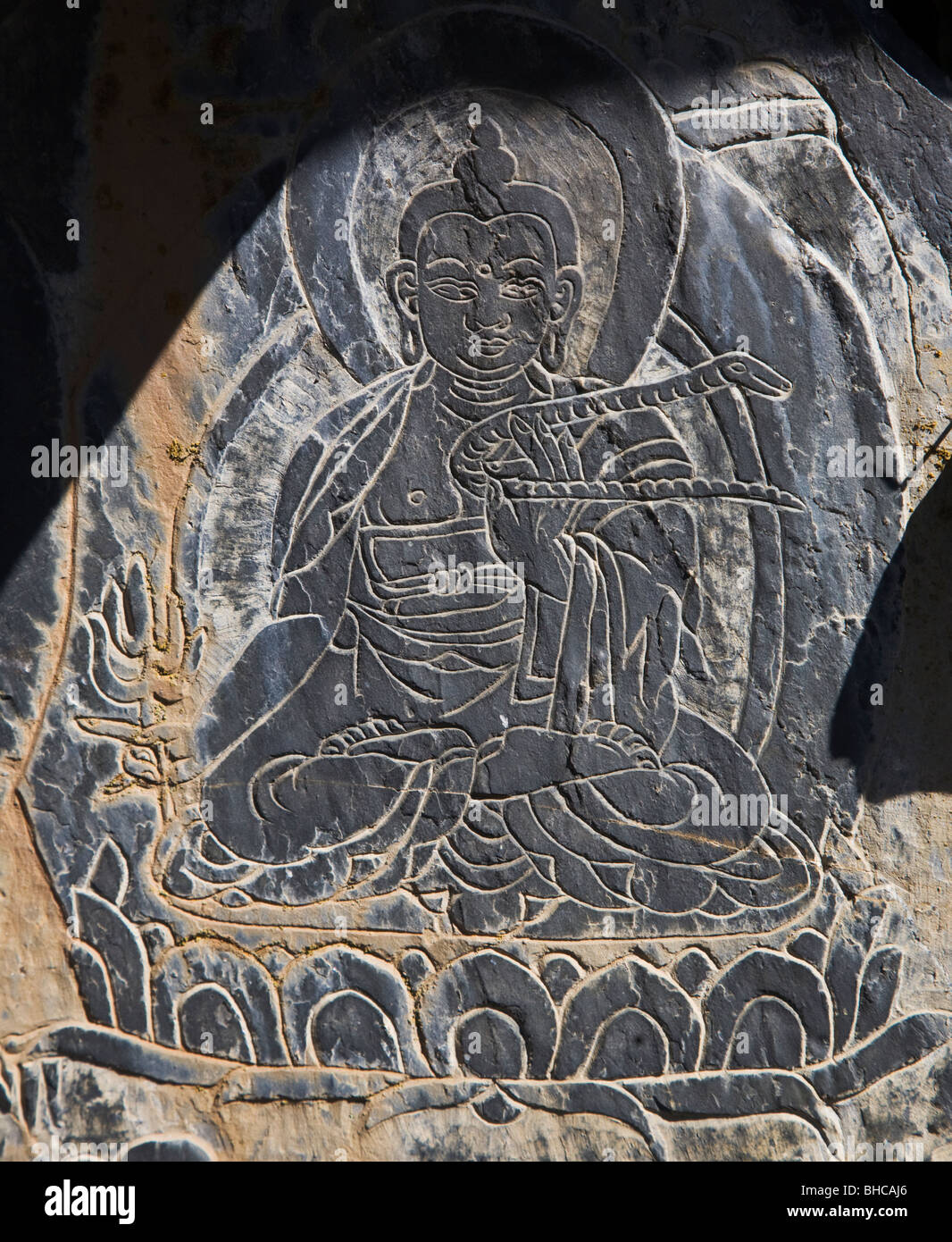 A MANI STONE carved with a BUDDHA holding a snake in the Tibetan area of NUPRI - AROUND MANASLU TREK, NEPAL Stock Photo