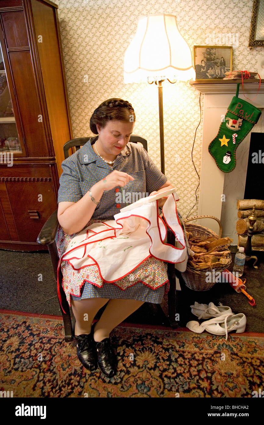 World War II woman actress sewing in 1940s style living room at Mid-Atlantic Air Museum World War II Weekend and Reenactment Stock Photo