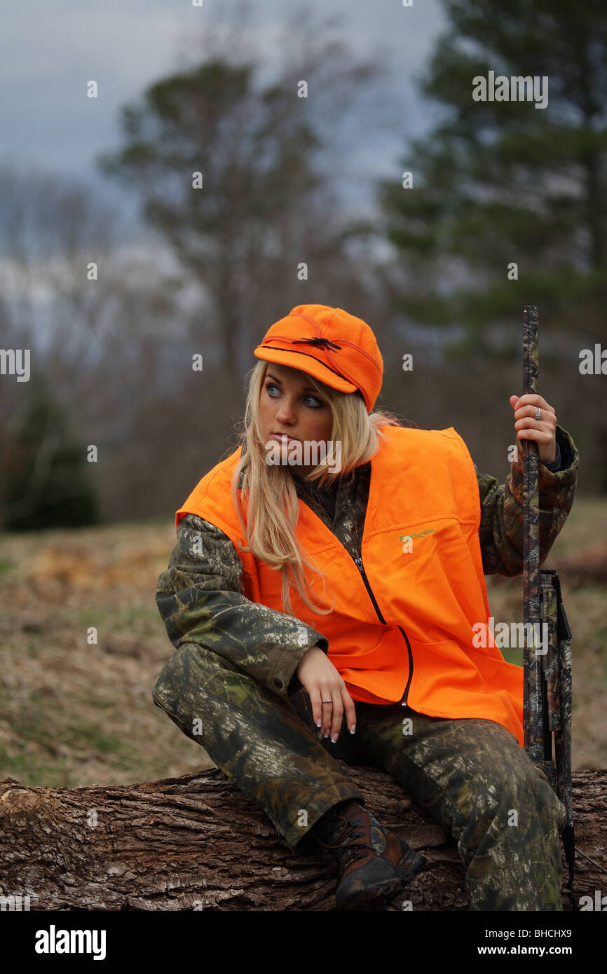 YOUNG WOMAN 21 Y.O. FEMALE HUNTER ORANGE BLAZE VEST STORMY KROMER HAT CARRYING RIFLE DEER HUNTING Stock Photo