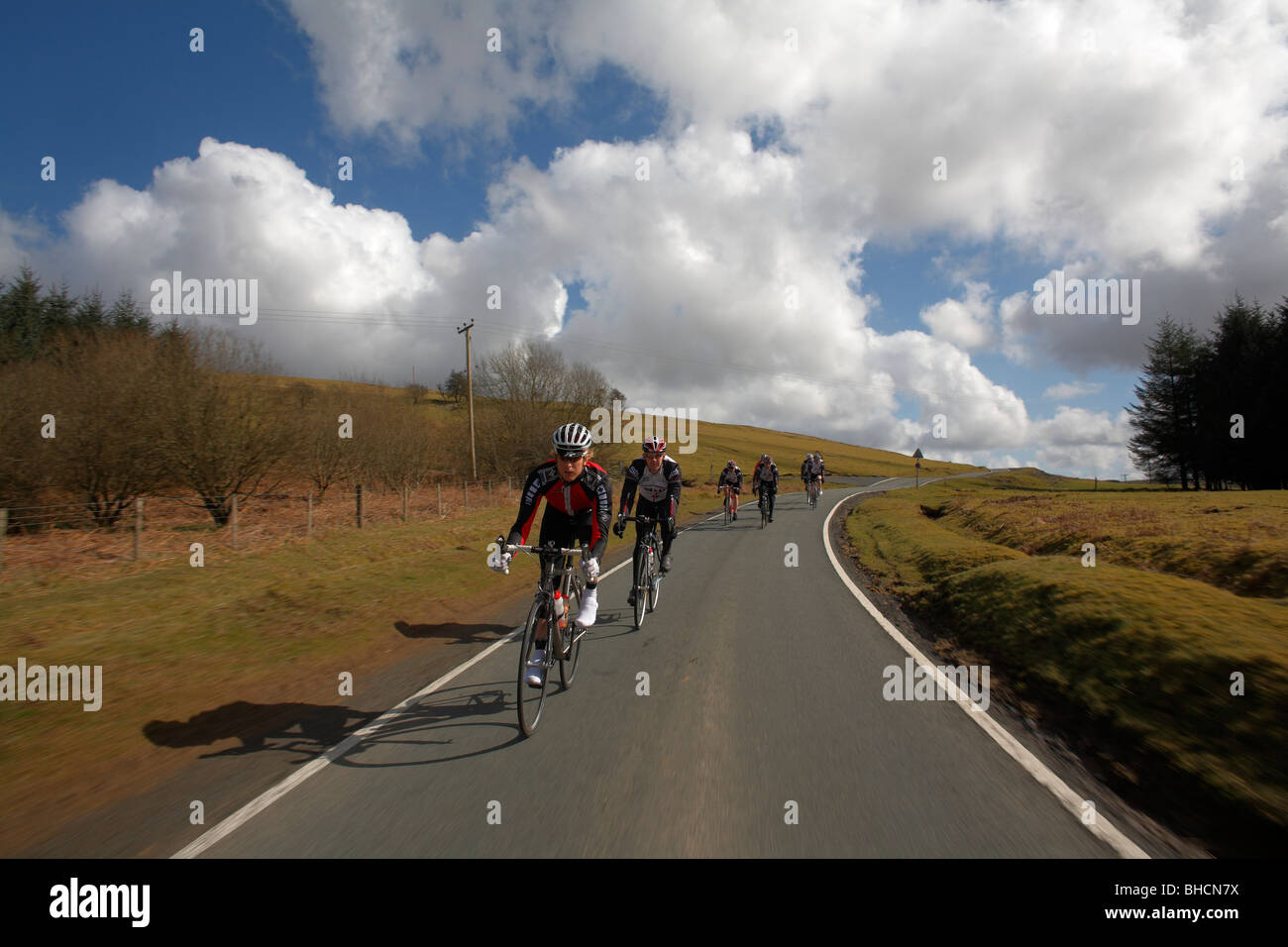 Peloton of cyclists ride down a closed road through the countryside Stock Photo