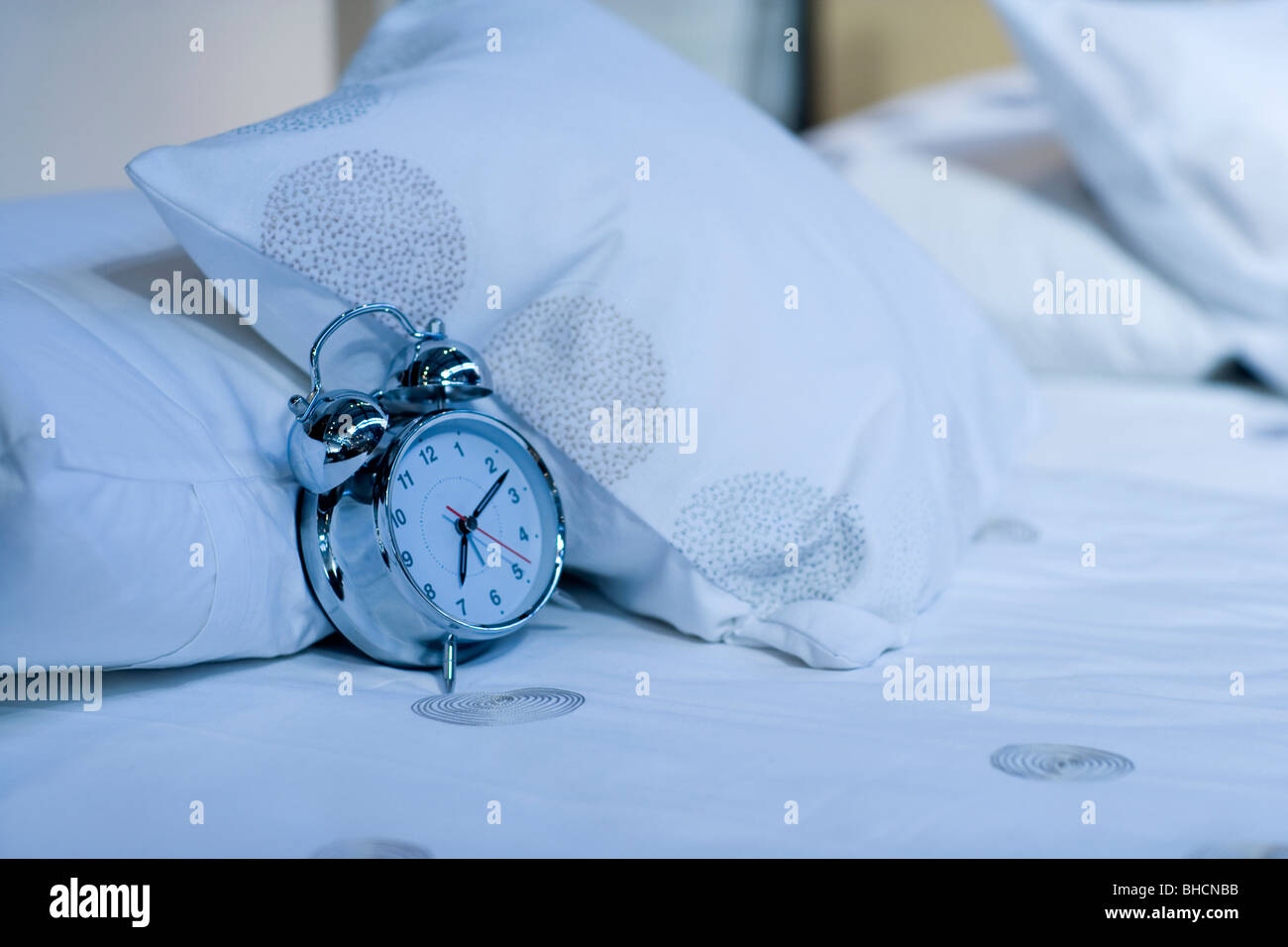 Alarm clock on bed Stock Photo - Alamy