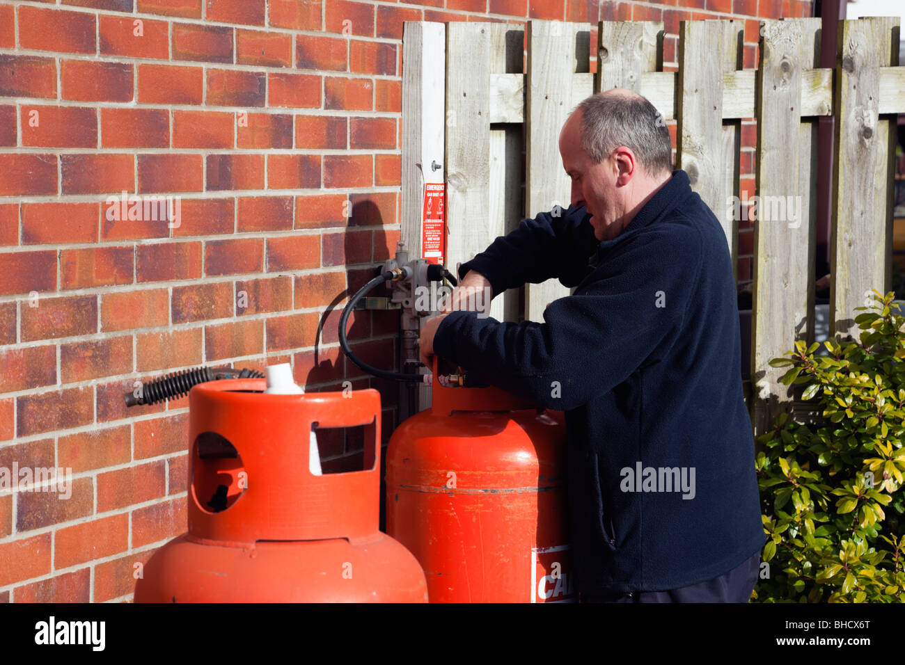 Workman changing a domestic calor gas bottle outside a house Stock
