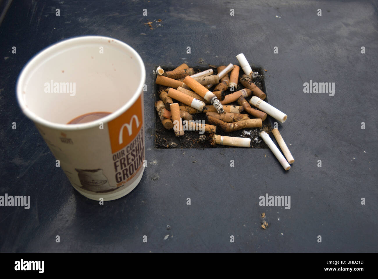 mcdonalds cigarettes discarded mcdonalds paper coffee cup and cigarette butts on a street  rubbish bin in kingston upon thames, surrey, england Stock Photo