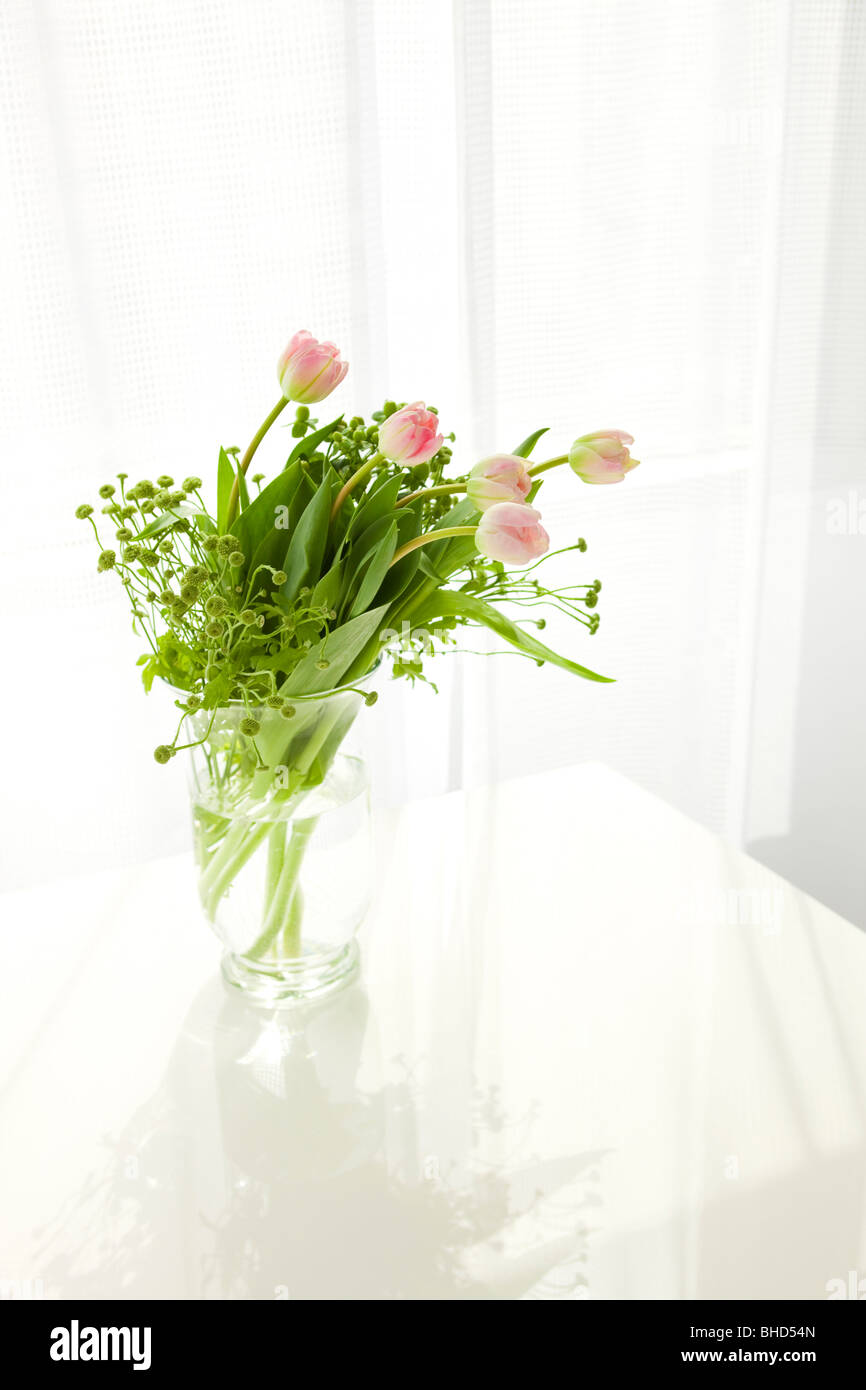 Vase of pink tulips on table Stock Photo