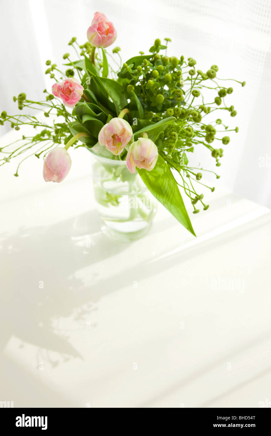 Vase of pink tulips on table Stock Photo