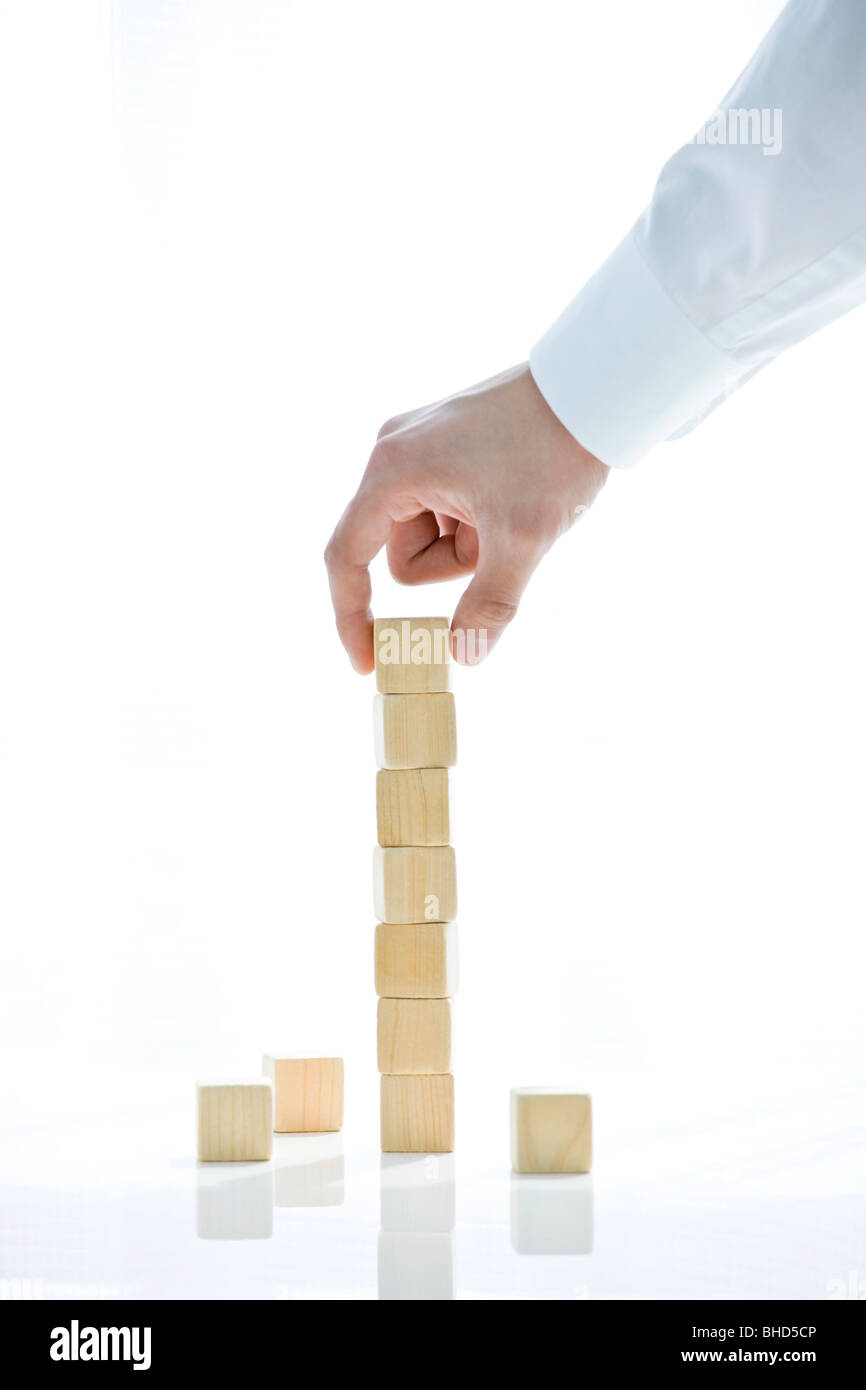 Man building a stack of building blocks Stock Photo