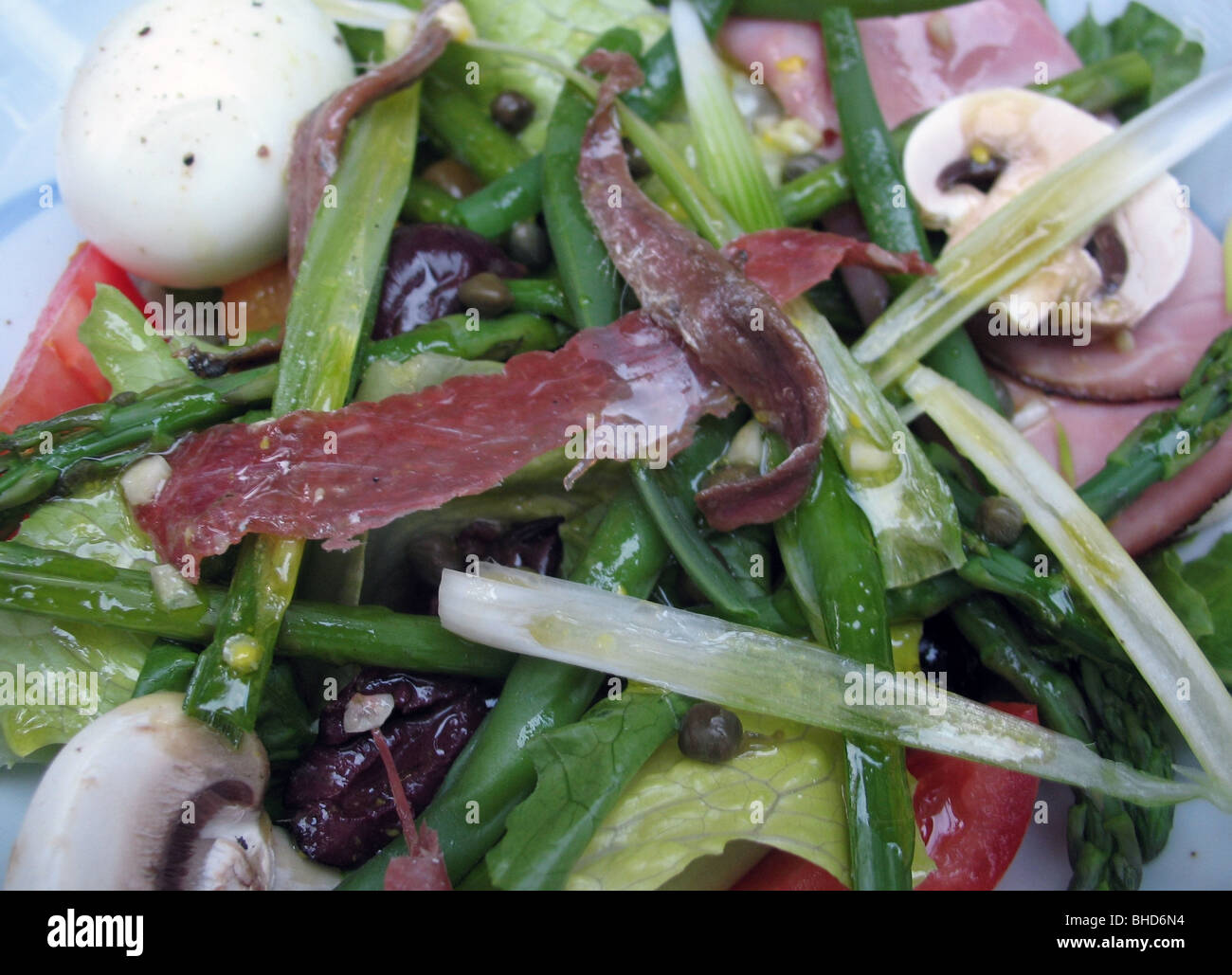 Meal salad with hard boiled eggs, anchovies, ham, green beans, olives