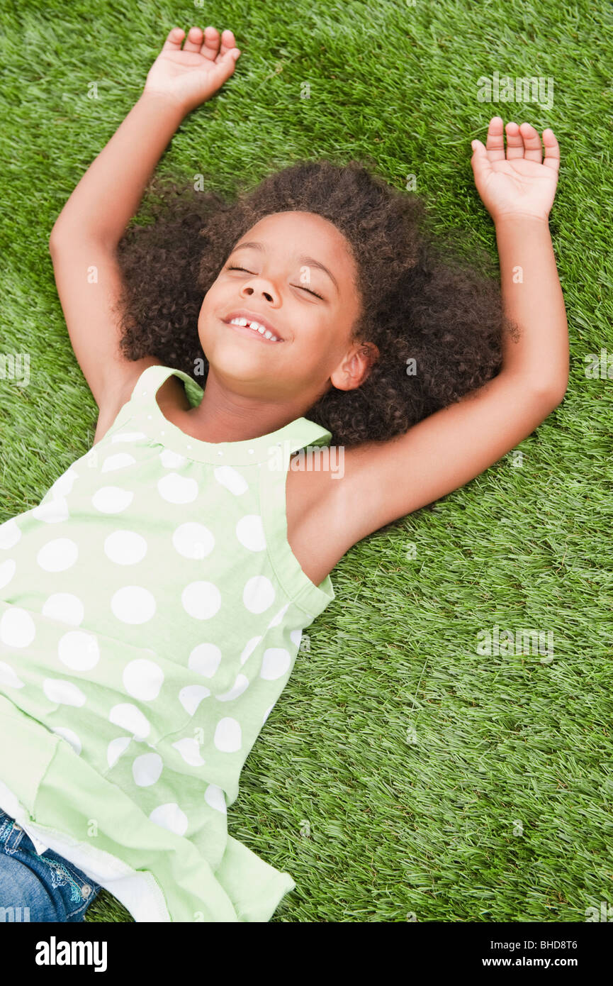 Mixed race girl laying in grass Stock Photo