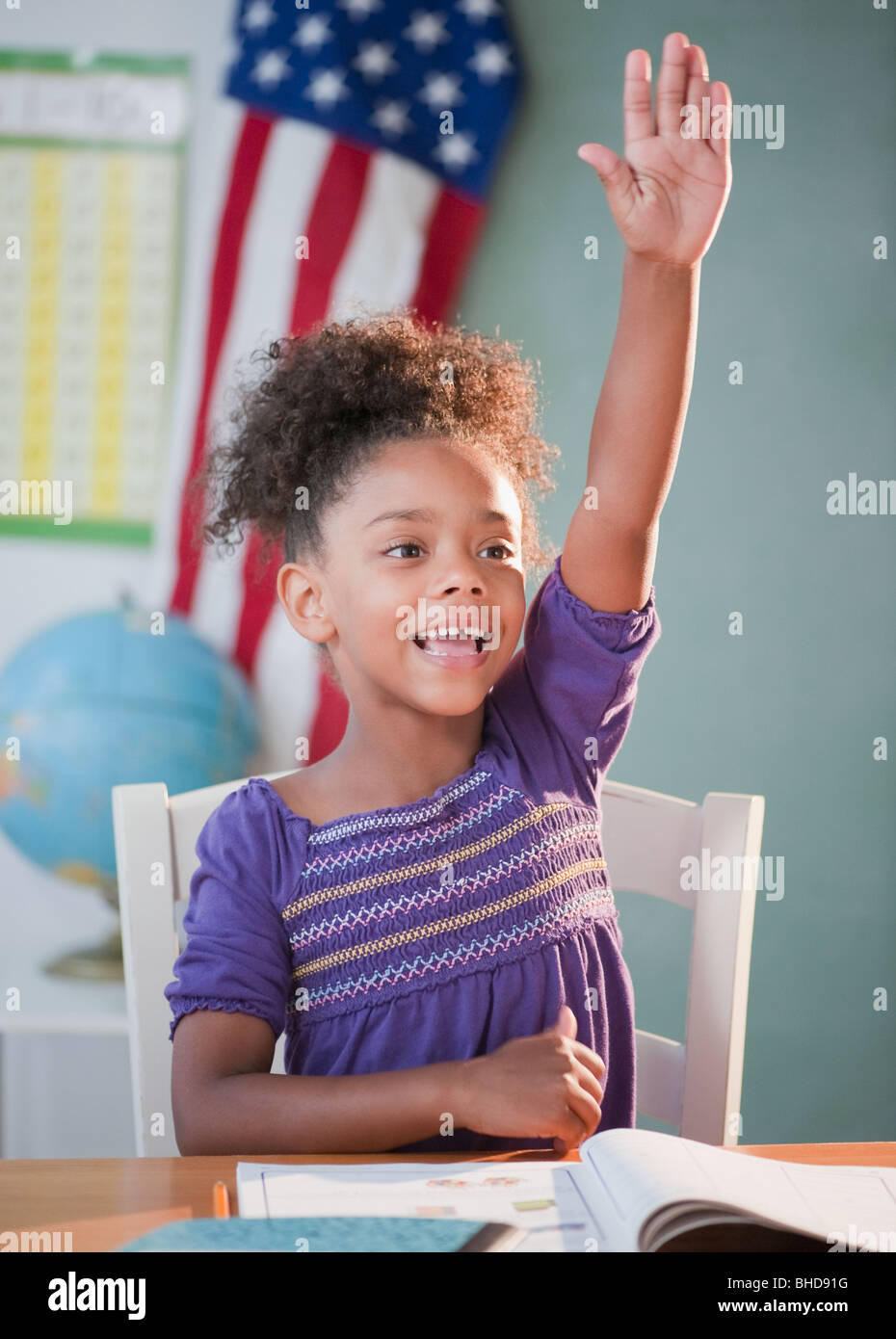 Mixed race girl answering question in classroom Stock Photo
