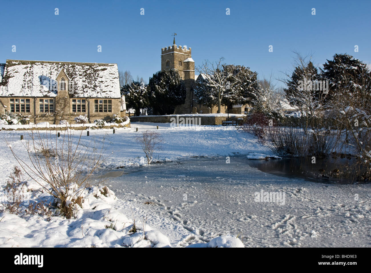 Ducklington pond, church and old school in snow Stock Photo