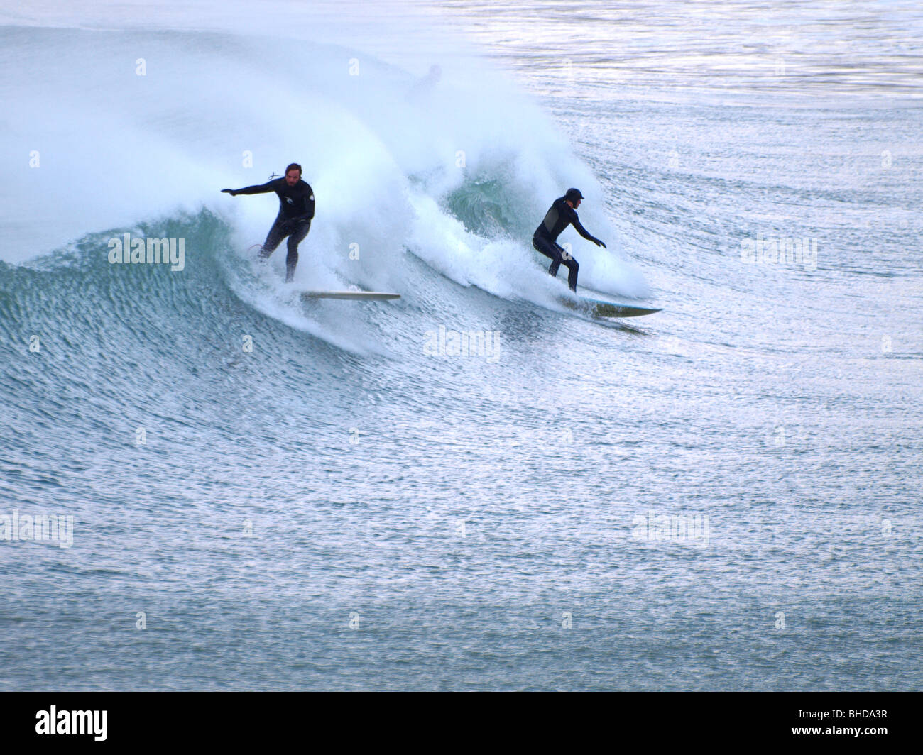 Two surfers on the same wave, Newquay, Cornwall Stock Photo