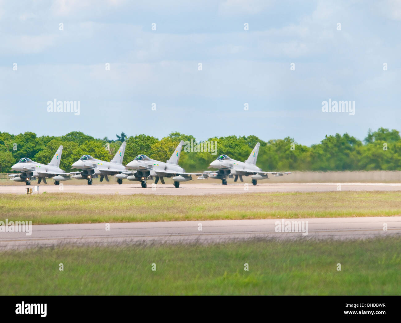 A rare sight of 4 Typhoon fighter jet aircraft lined up side by side ready for takeoff on the main runway at RAF Conningsby Stock Photo