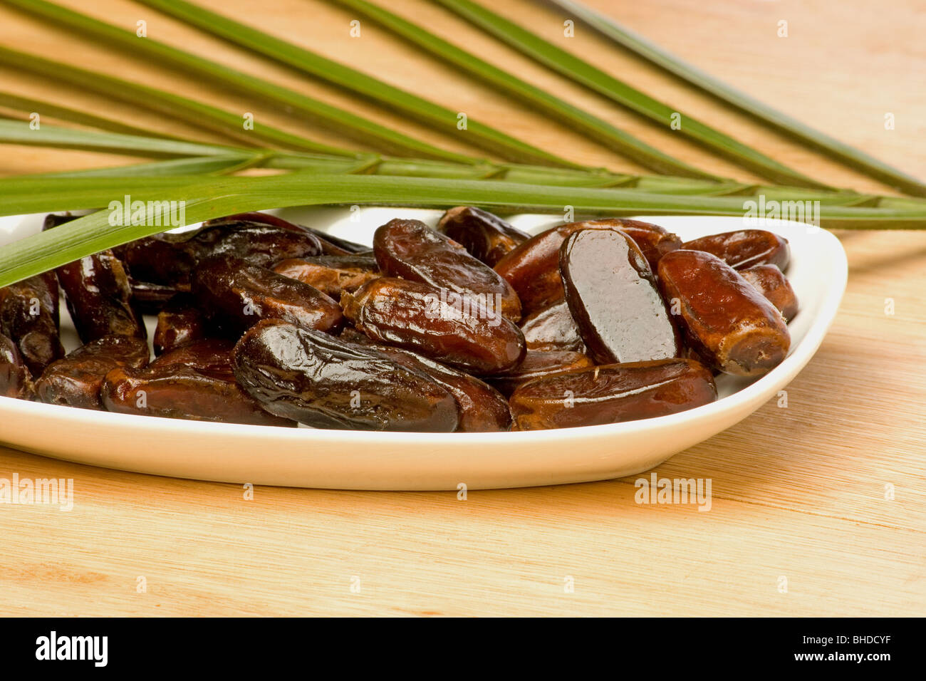Close-up of dried dates and palm fronds on wooden  background Stock Photo