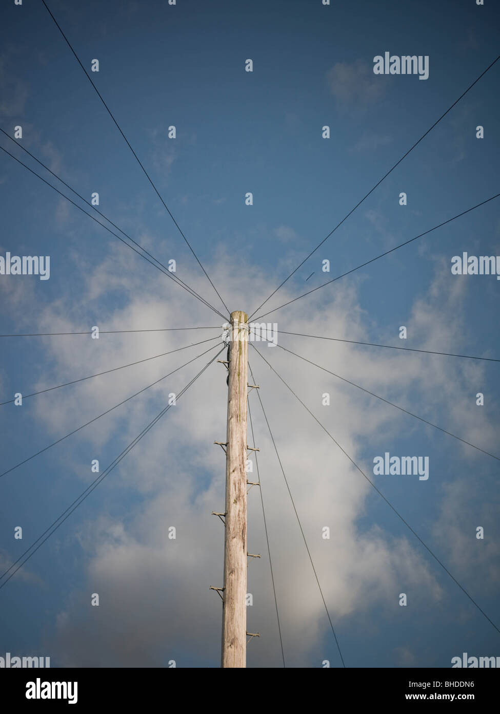 Wooden telegraph pole with phone lines against blue sky. Stock Photo
