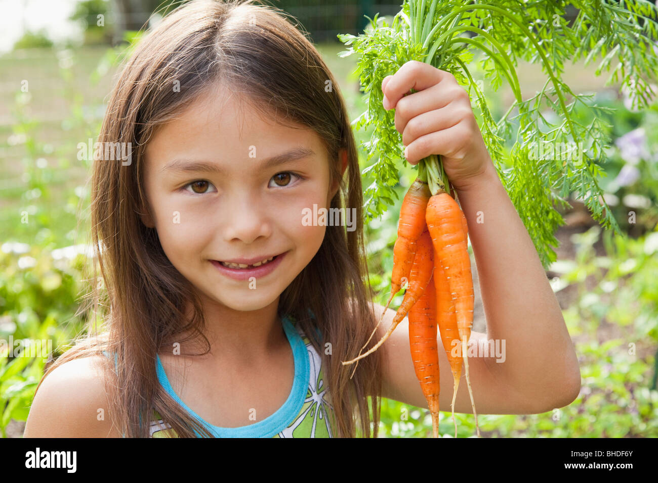 Mixed race girl holding carrots Stock Photo