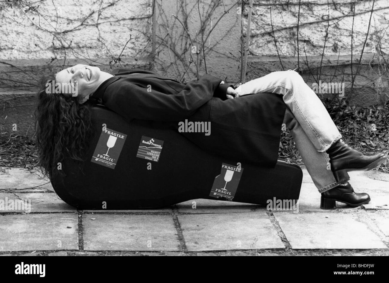 Crow, Sheryl, * 11.2.1962, US musician, singer, full length, lying on guitar case, 1995, Stock Photo