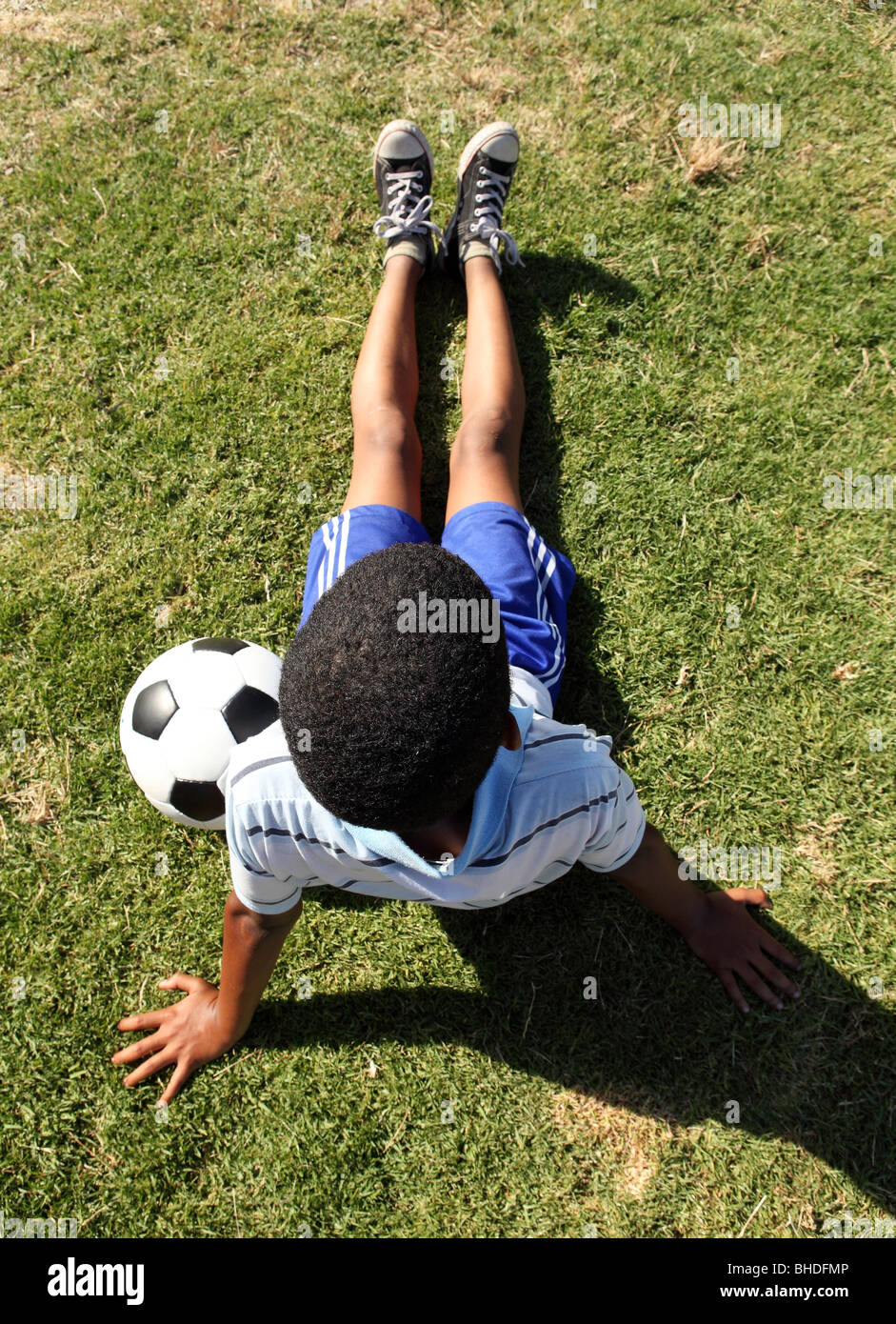 A boy sits with a soccer ball while watching a soccer game in Cape Town