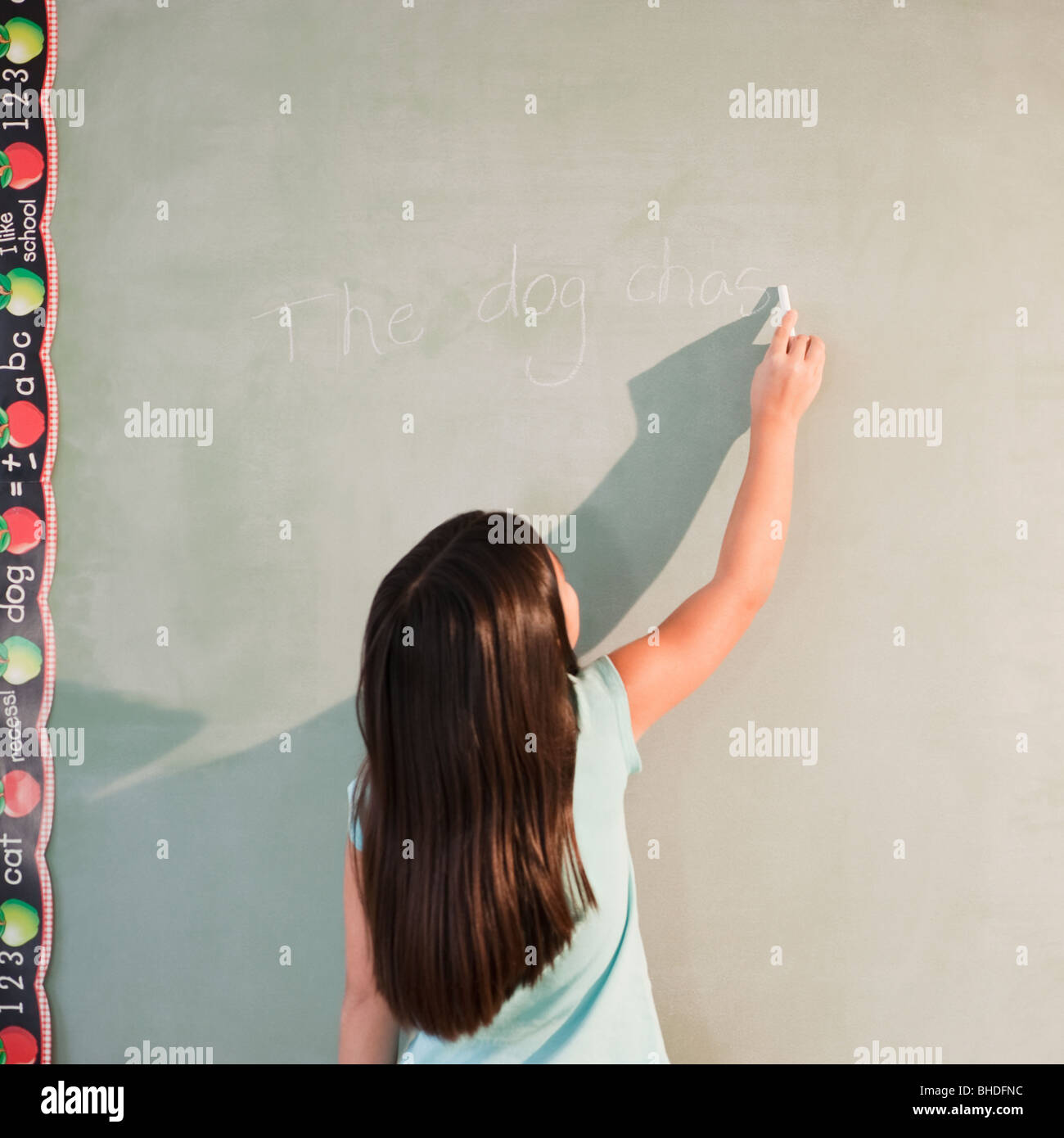 Mixed race girl writing on blackboard Stock Photo
