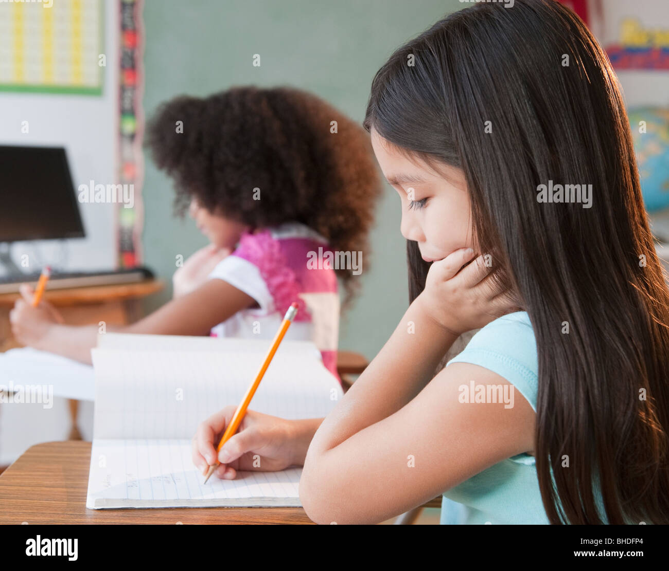 Mixed race school girl writing in notebook Stock Photo