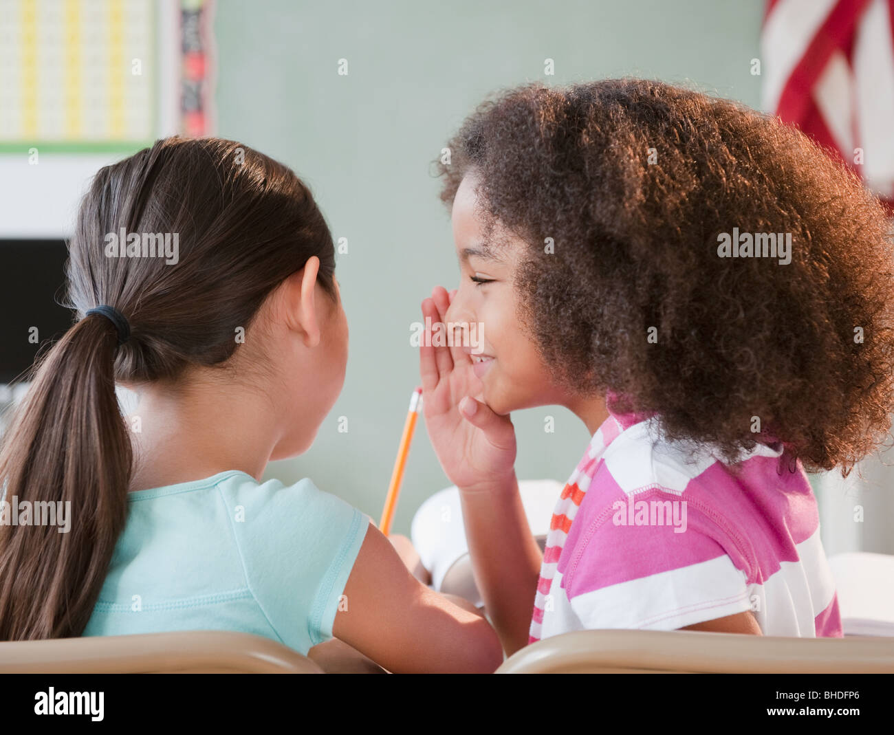 School girl whispering to friend Stock Photo