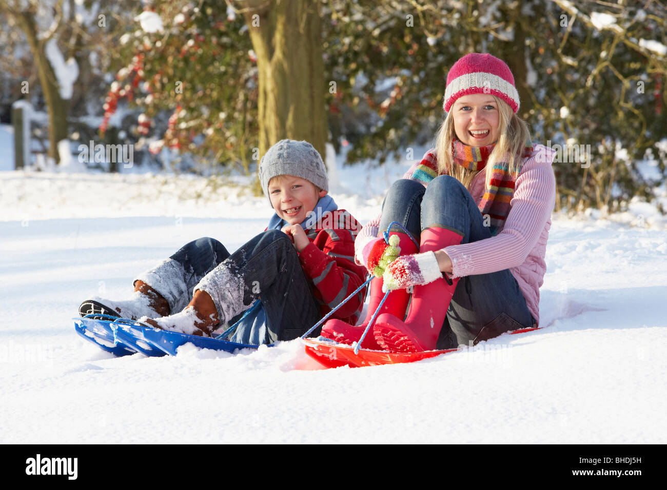 Mother Riding On SledgesThrough Snowy Landscape Stock Photo