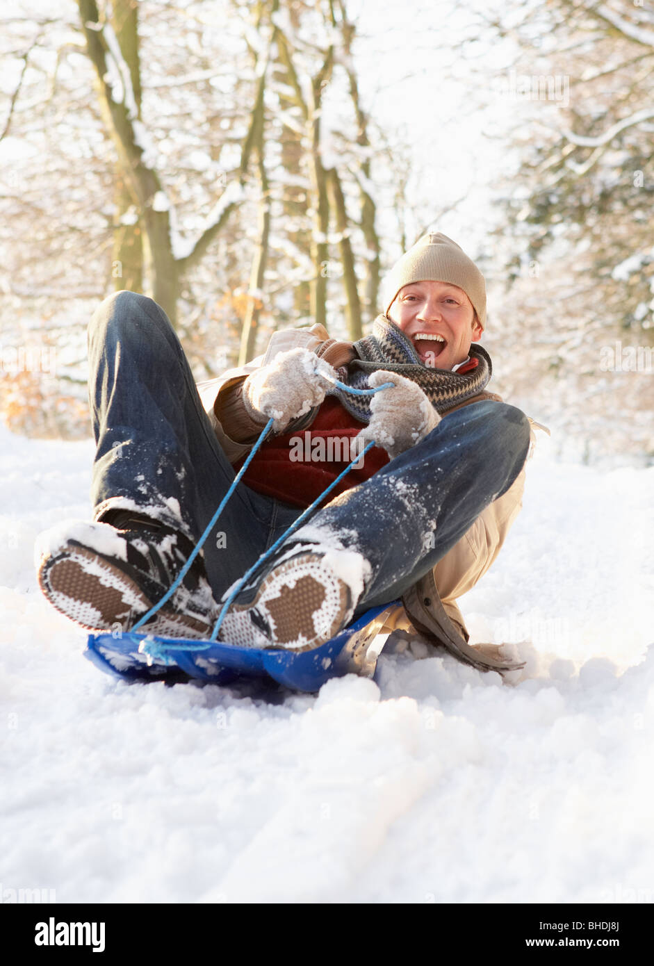 Man Sledging Through Snowy Woodland Stock Photo