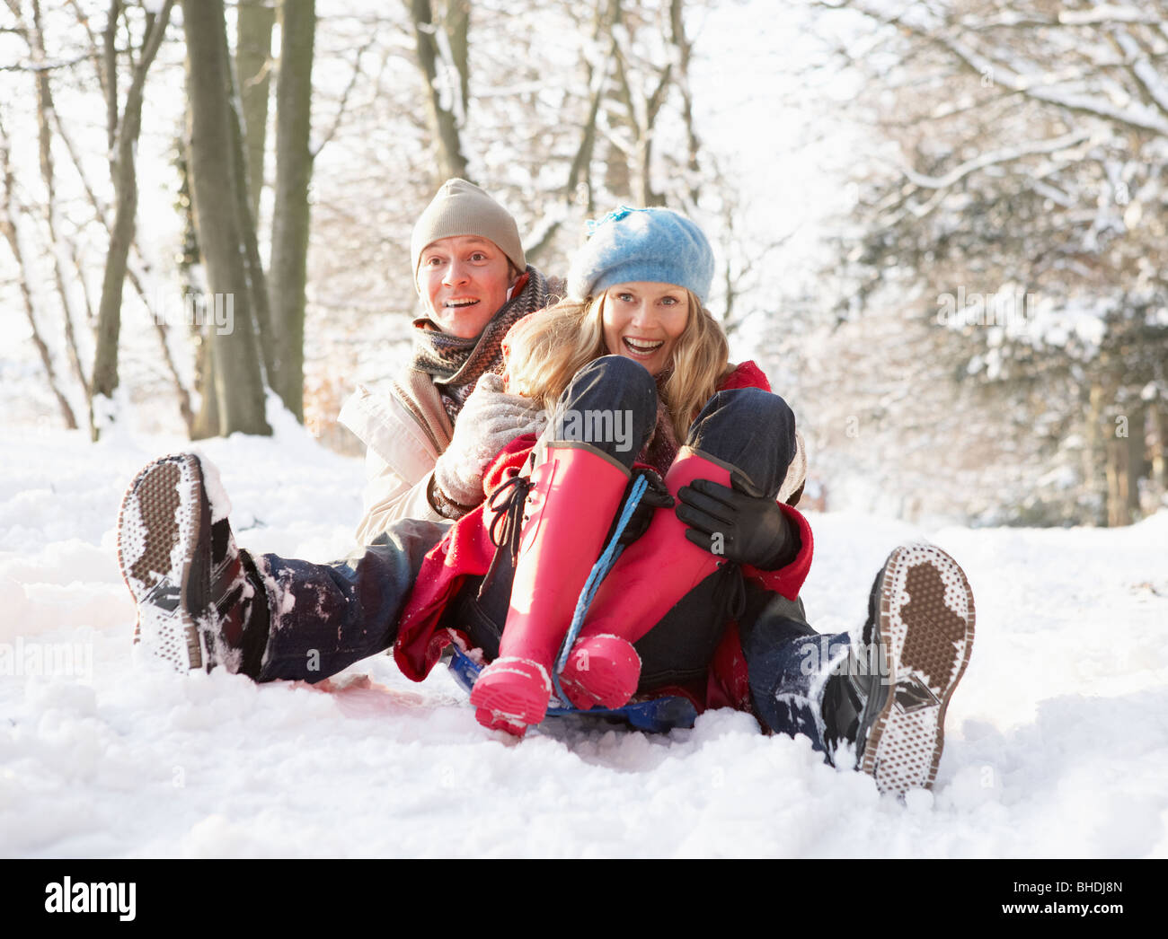 Couple Sledging Through Snowy Woodland Stock Photo