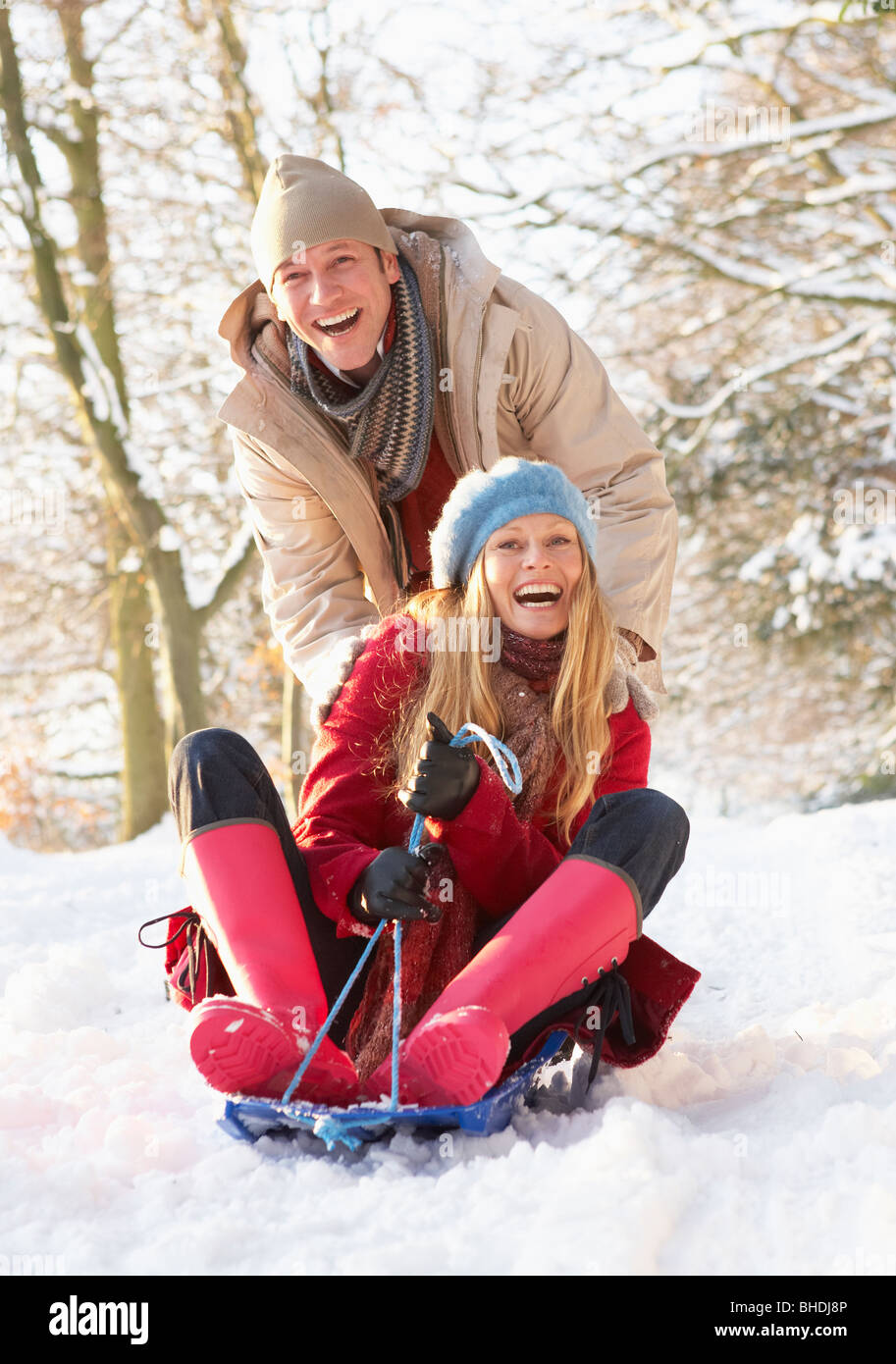Couple Sledging Through Snowy Woodland Stock Photo