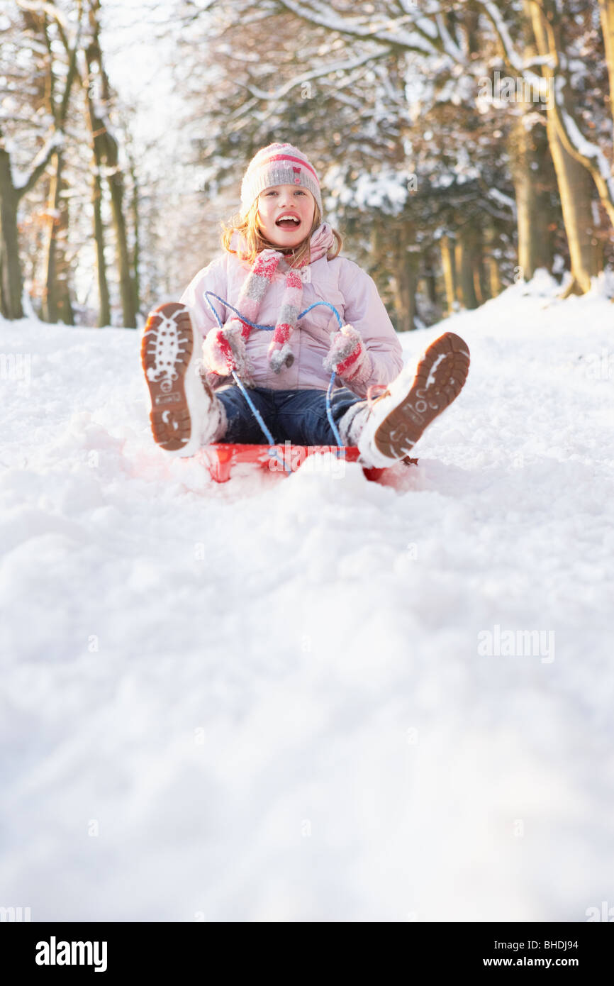 Girl Sledging Through Snowy Woodland Stock Photo