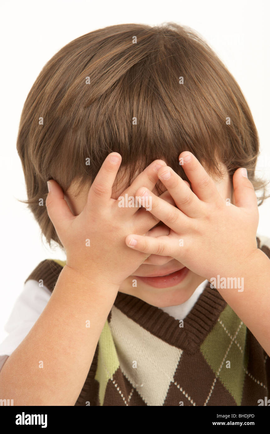 Studio Portrait Of Young Boy Covering Eyes Stock Photo