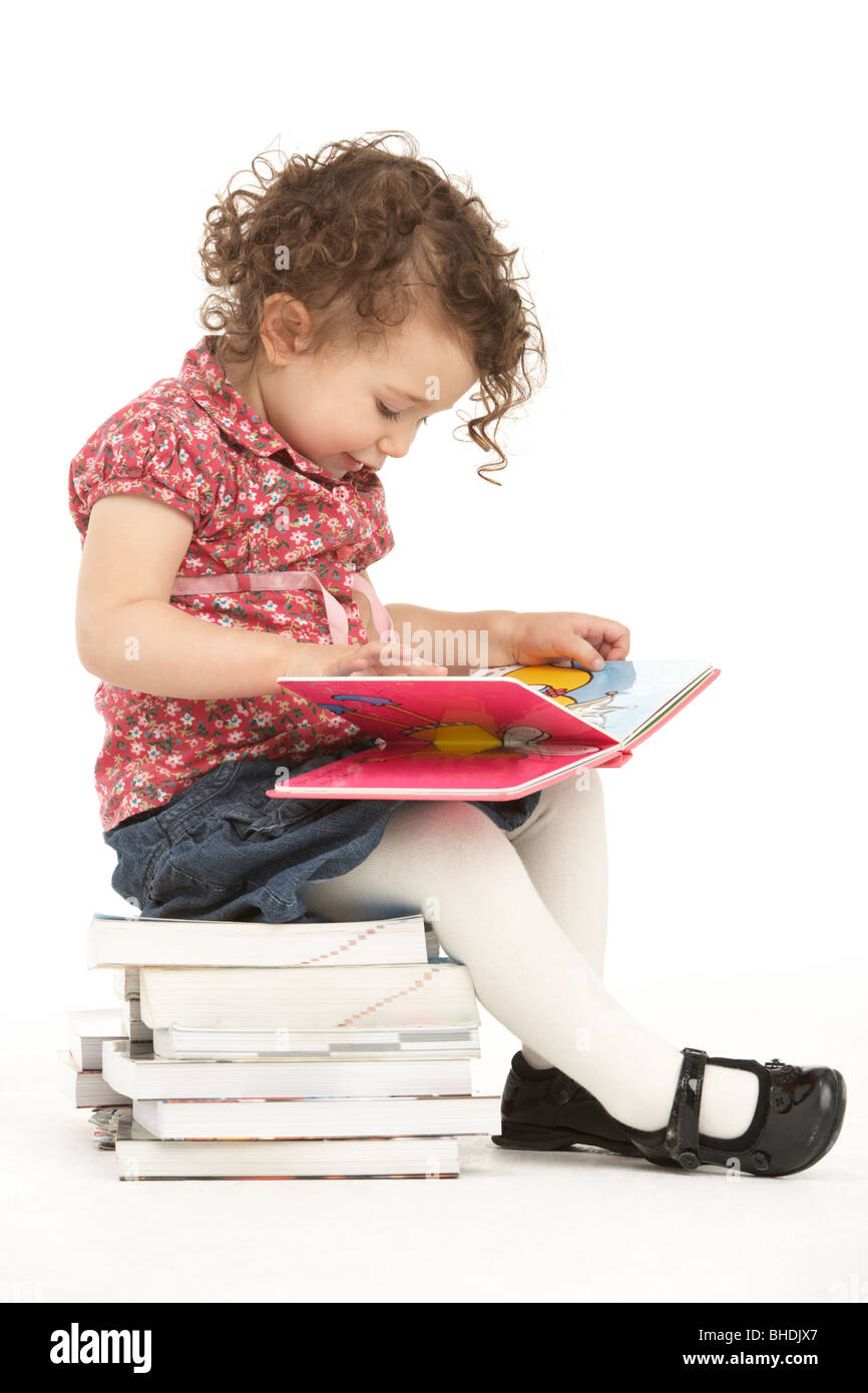 Young Girl Sitting On Pile Of Books Reading Stock Photo