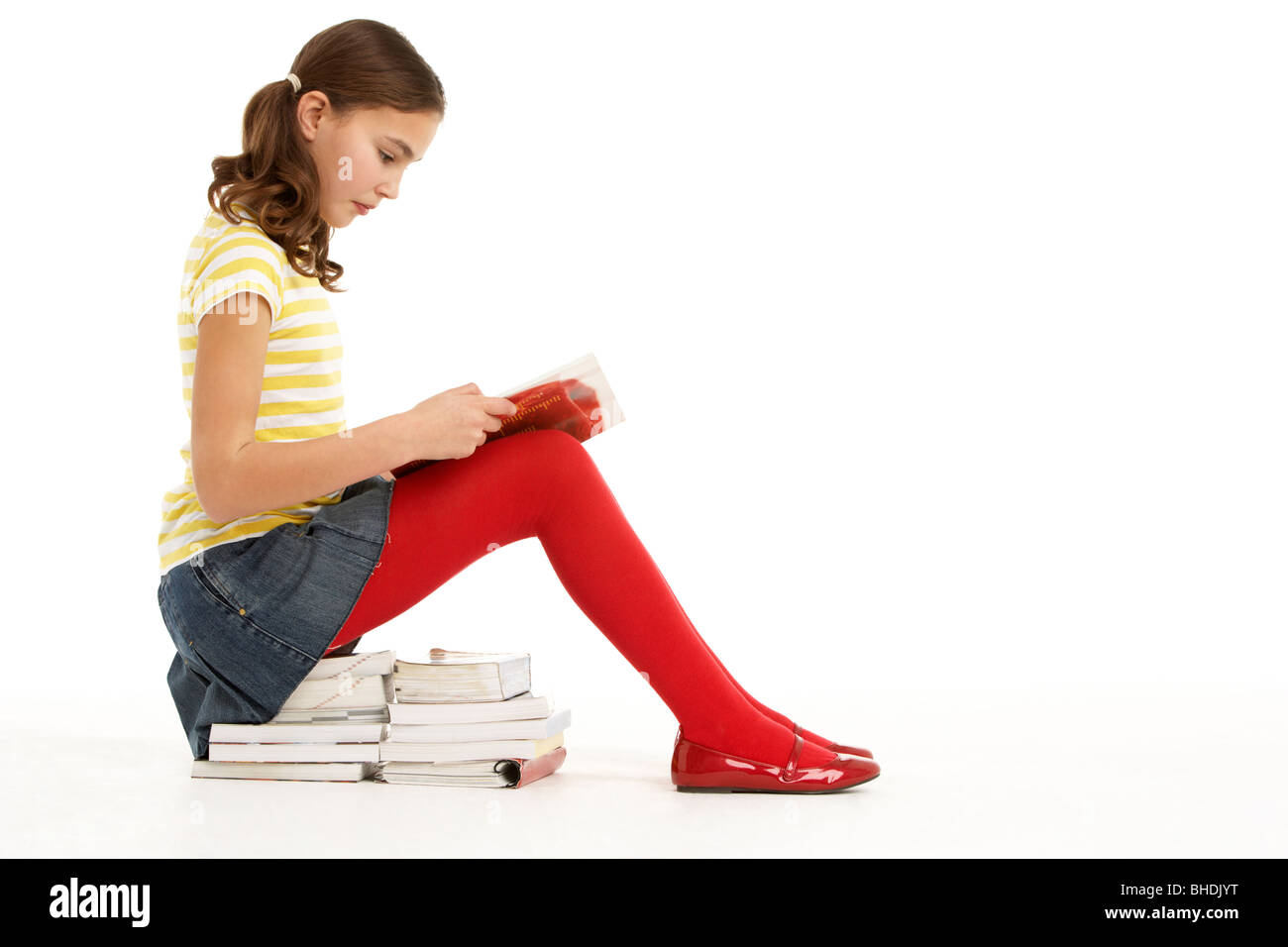Young Girl Sitting On Pile Of Books Reading Stock Photo - Alamy