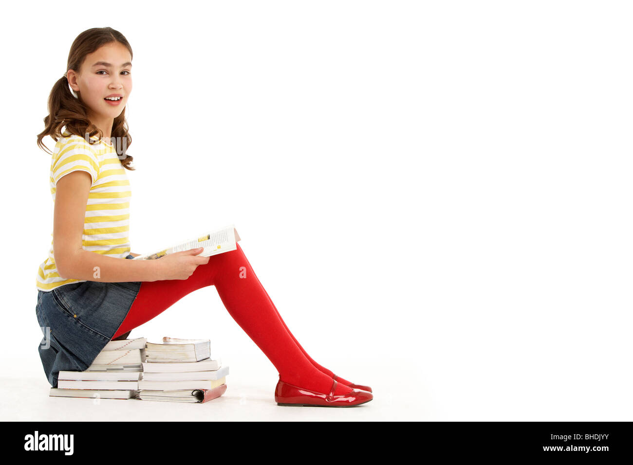 Young Girl Sitting On Pile Of Books Reading Stock Photo - Alamy