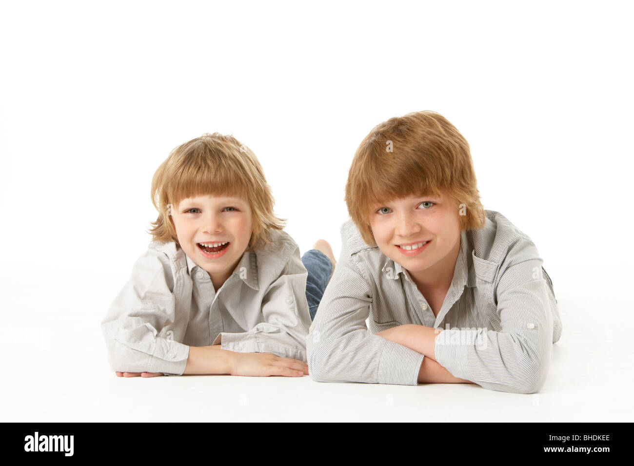 Two Young Boys Lying On Stomach In Studio Stock Photo