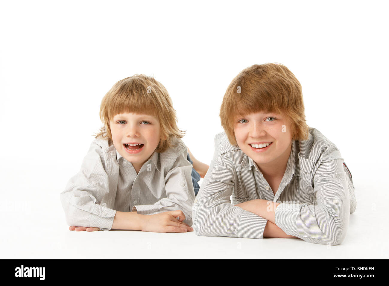 Two Young Boys Lying On Stomach In Studio Stock Photo