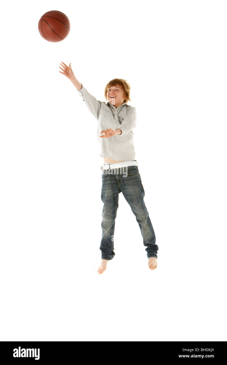 Young Boy Jumping With Basketball In Studio Stock Photo