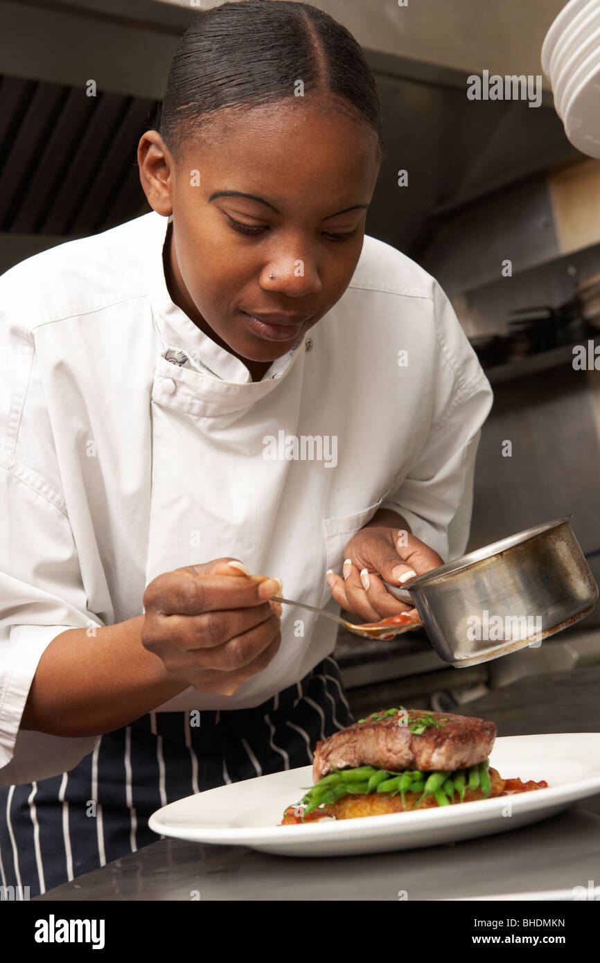 Chef Adding Sauce To Dish In Restaurant Kitchen Stock Photo