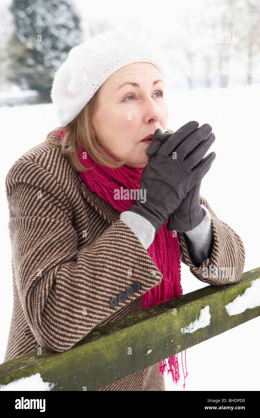 Senior Woman Standing Outside In Snowy Landscape Warming Hands Stock Photo