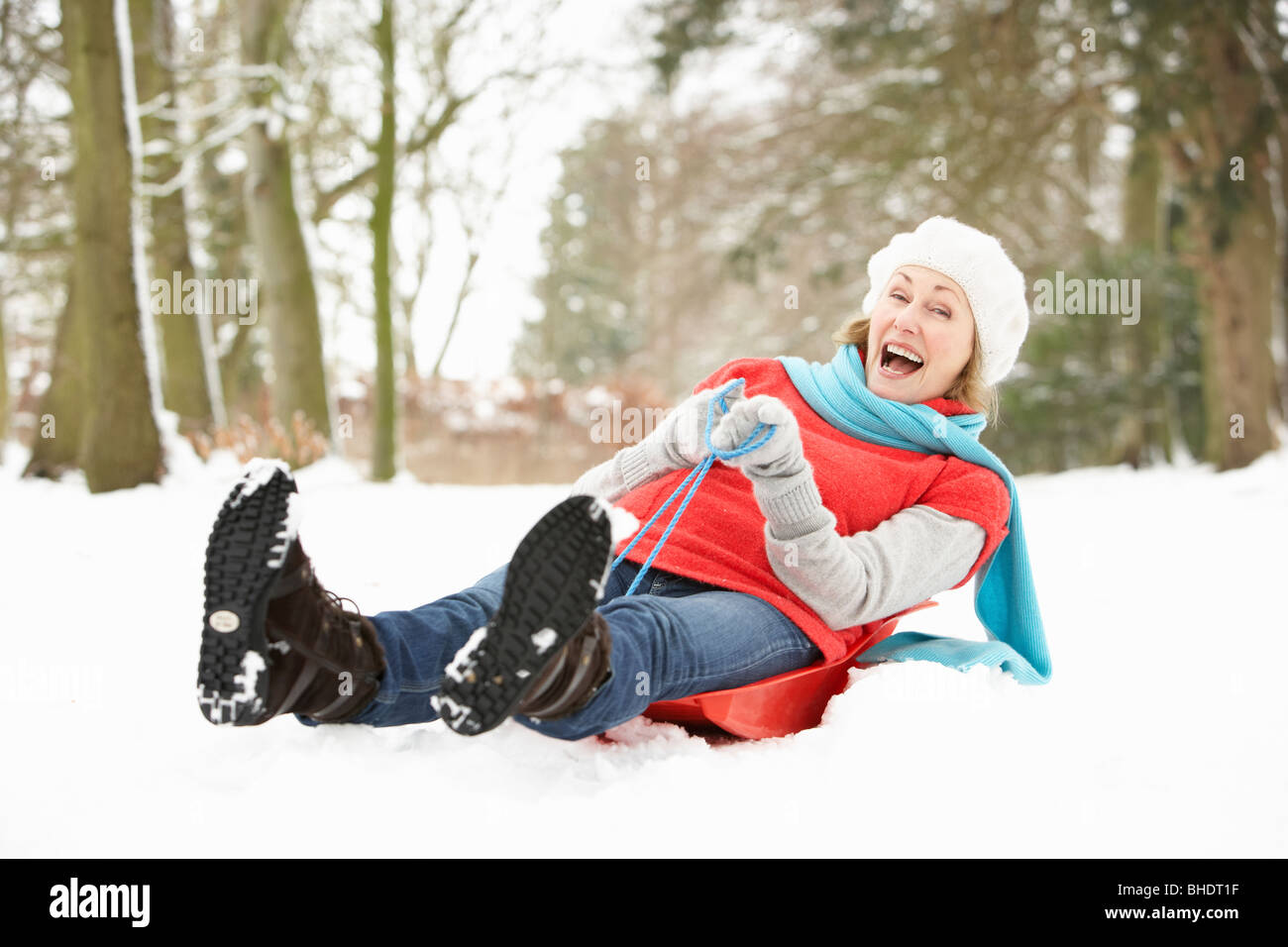 Senior Woman Sledging Through Snowy Woodland Stock Photo