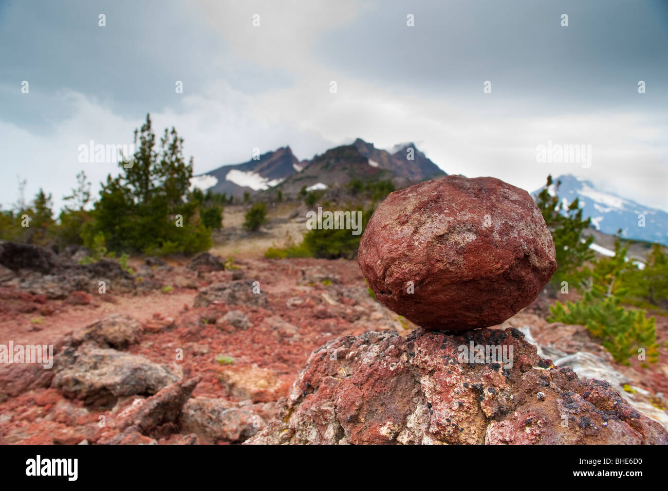 Red rock balancing on another rock, Broken Top mountain Stock Photo - Alamy