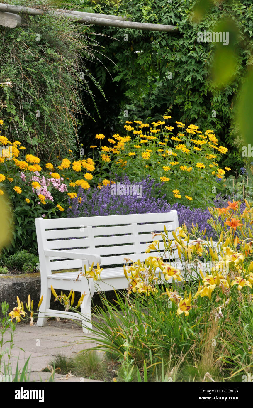 White bench in a perennial garden Stock Photo