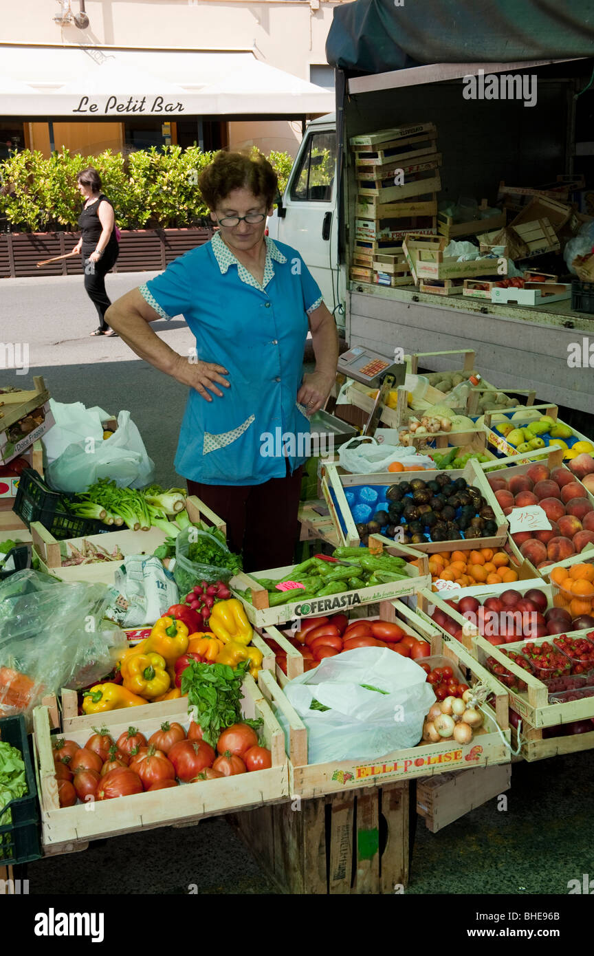 Woman at her market stall selling fruit and vegetables in Pinerolo ...