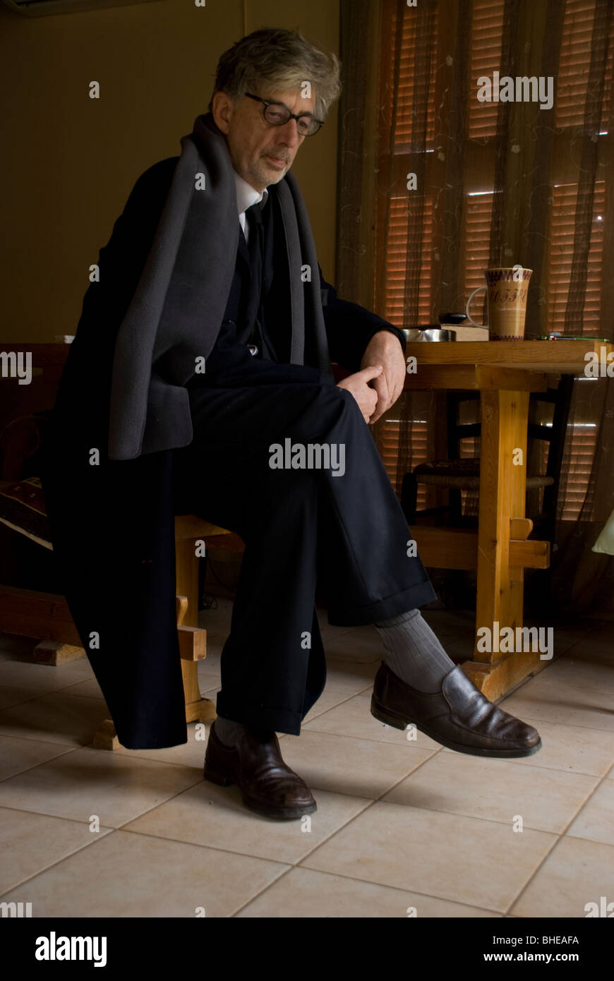 suited man sitting at a kitchen table Stock Photo