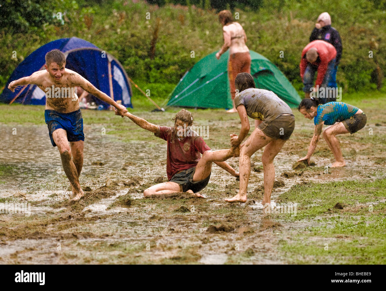 Youths playing in mud on a flooded Lake District campsite after torrential rain Stock Photo