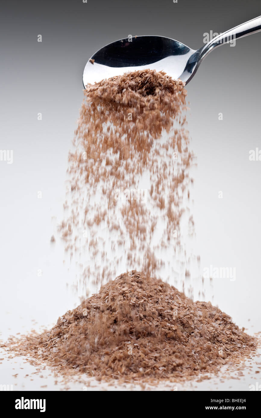 Pile of high fibre wheat bran spilling and a heaped dessert spoon Stock
